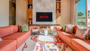 A modern living room with a large flat-screen TV, two sofas, a coffee table, and a patterned rug. - Villa Cyrine (Marrakech)