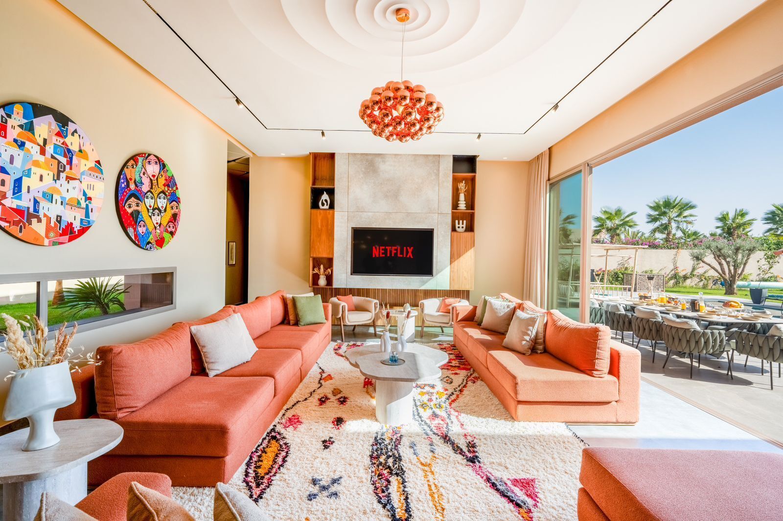 A modern living room with a large flat-screen TV, two sofas, a coffee table, and a patterned rug.