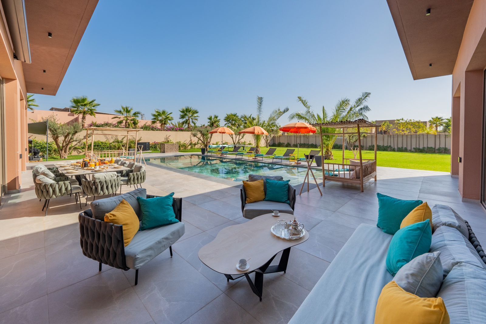 A modern outdoor patio with a pool, seating area, and umbrellas.