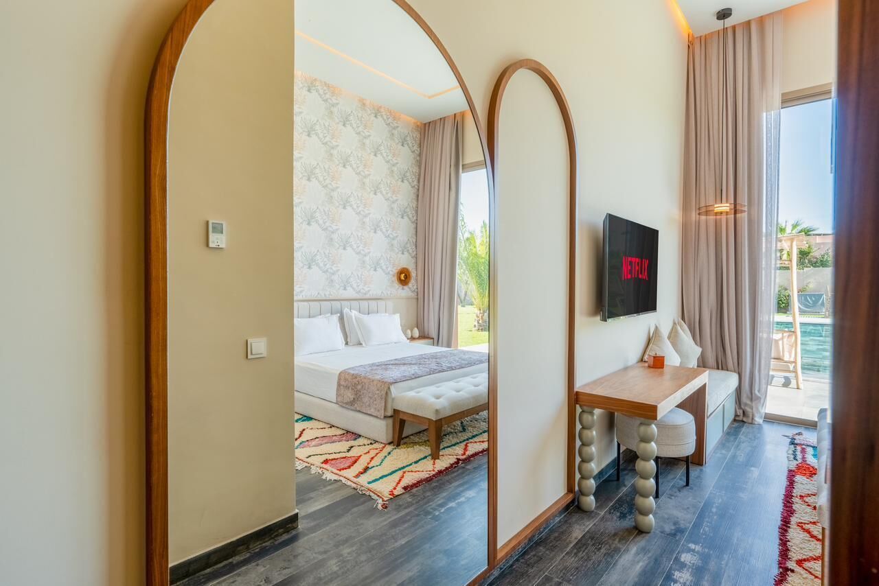 A hotel room with a bed, a desk, a TV, and a view of the outdoors.