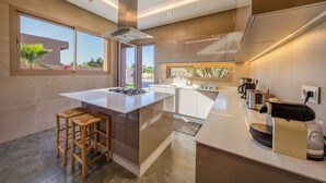 A modern kitchen with a central island, built-in appliances, and large windows. - Villa Cyrine (Marrakech)
