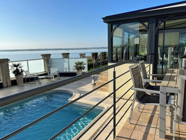 Ein Balkon mit Pool, Sitzgelegenheit im Freien und Blick auf das Meer.
