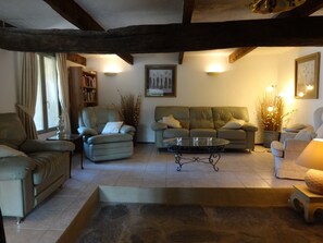A cozy living room with a sofa, armchairs, a coffee table, and a bookshelf.