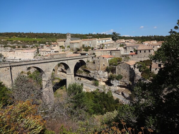 A stone bridge with arches, a town with historic buildings, and a hilly landscape.