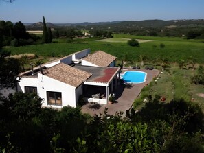 Ein Haus mit Swimmingpool, umgeben von viel Grün und Hügeln.