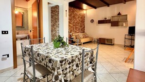 A dining area with a table set for four, a potted plant, and a view of a kitchen and living area. - Steps from the Sea, Minutes from Cefalù (Campofelice di Roccella)