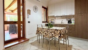 A spacious kitchen with a dining area, featuring a wooden door, tiled flooring, and a hanging light fixture. - Steps from the Sea, Minutes from Cefalù (Campofelice di Roccella)