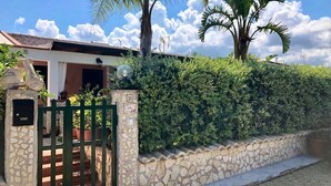 A stone wall, a metal gate, and a house with a tiled roof. - Steps from the Sea, Minutes from Cefalù (Campofelice di Roccella)