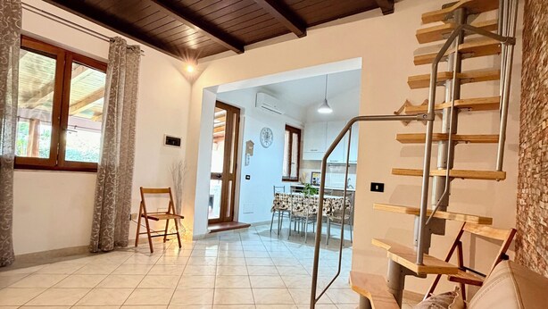 A spacious living area with a leather sofa, a staircase, and a dining area in the background. - Steps from the Sea, Minutes from Cefalù (Campofelice di Roccella)