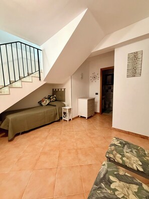 Quarto com cama, uma mesinha, cômoda e escada.