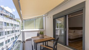 Ein Balkon mit Tisch, Stühlen, einer Topfpflanze und Blick auf ein gegenüberliegendes Gebäude.