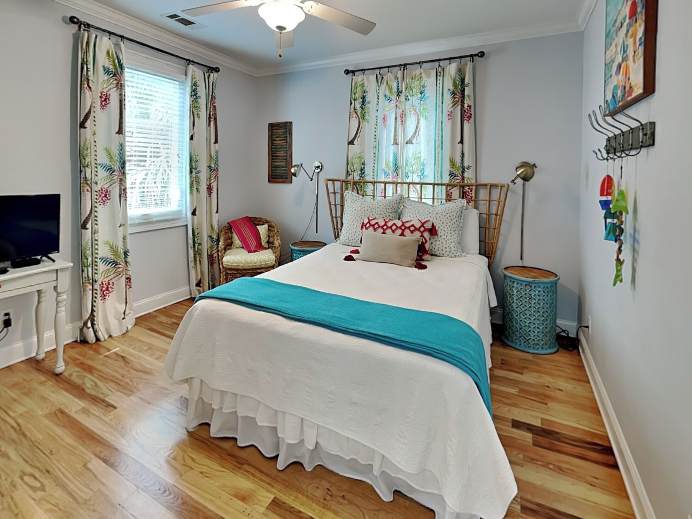 Une chambre à coucher avec un lit, une chaise, un téléviseur et un ventilateur de plafond.