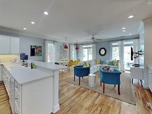 A spacious living area with a central island, a dining table, and a sofa with colorful cushions. - Chu Cottage (Tybee Island)