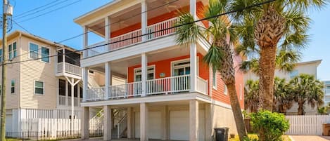 A two-story building with a balcony, a garage, and a palm tree in the foreground.