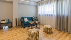 Uma sala de estar moderna com um sofá, pufes, uma mesa de centro e um letreiro na parede.