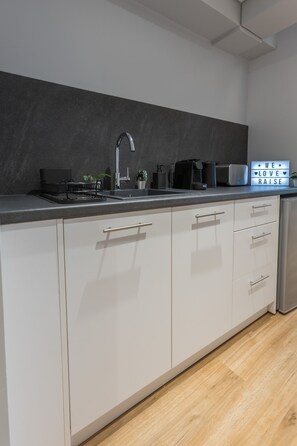 Eine moderne Küche mit schwarzem Arbeitsplatz, Edelstahlspüle und weißen Schränken.