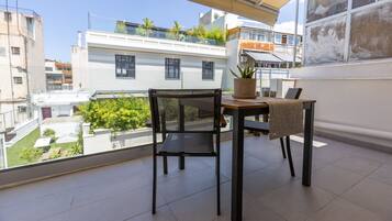 Un balcon avec une table et une chaise, un pot de fleurs et une vue sur le paysage urbain.