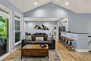 A modern living room with a sofa, coffee table, and bar stools.