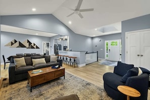 A modern living room with a sofa, coffee table, and a dining area with stools.
