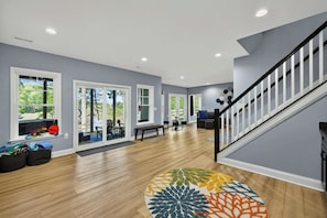 A spacious living area with a wooden floor, a staircase, and a view of the outdoors.