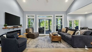 Ein modernes Wohnzimmer mit Flachbildfernseher, Sofas, einem Couchtisch und einem Kamin.