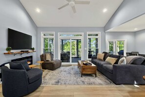 A modern living room with a flat-screen TV, sofas, a coffee table, and a fireplace.