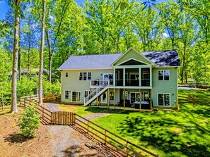 A two-story house with a porch, surrounded by trees.
