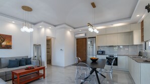Una cuina moderna amb armaris blancs, una illa central i zona de dinar amb taula i cadires.