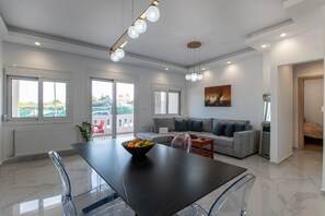 Un salon moderne avec un canapé, une table à manger et des chaises, ainsi qu’une grande fenêtre.