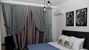 Camera da letto con un letto, tende, opere d'arte a parete e un condizionatore.