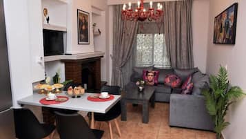 Un salon comprenant un canapé, une table à manger avec des chaises, une cheminée et un lustre.