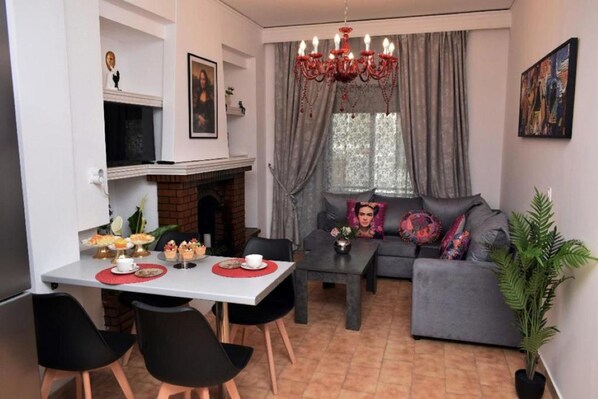 Ein Wohnzimmer mit einer Couch, einem Esstisch mit Stühlen, einem Kamin und einer Chandelier.