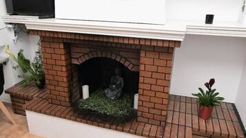 Une cheminée en briques ornée d’une statue, d’une plante en pot et d’un mur blanc.