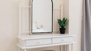 A white vanity with a mirror, a small stool, and a potted plant. - Alexandros Luxury Apartments Nydri (Rachi)