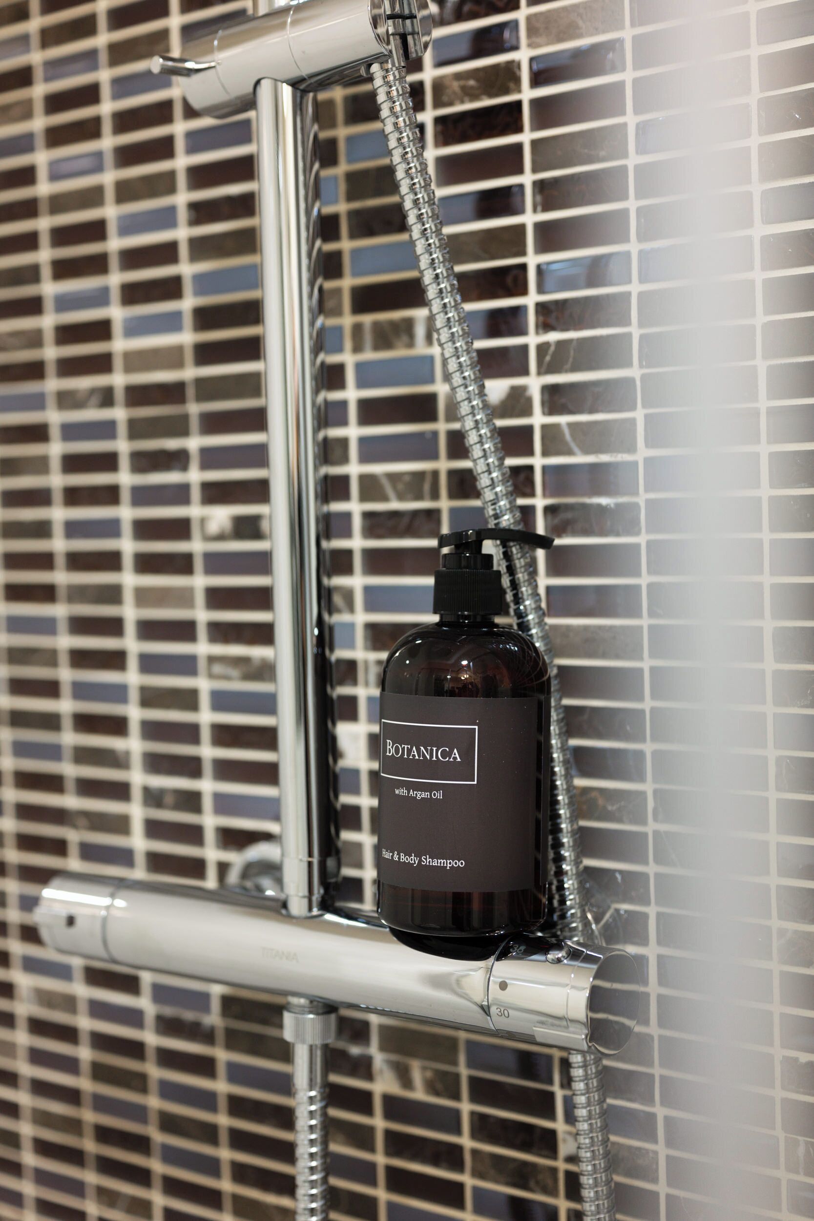 A shower with a bottle of Botanica body shampoo.