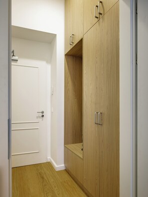Ein Flur mit einer weißen Tür, einem Holzschrank mit Griffen und einem Lichtschalter an der Wand.
