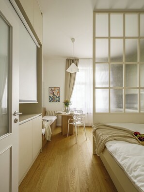 Ein Schlafzimmer mit einem Bett, einem Schreibtisch mit Stühlen, einem Fenster mit Jalousien und einer Tür.