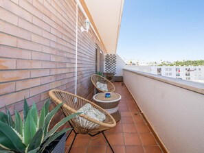 Ein Balkon mit zwei Korbstühlen, einem kleinen Tisch und einem Blumentopf.