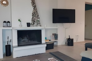 A modern living room with a fireplace, a mounted TV, and a stone accent wall.