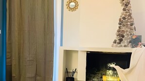 Ein modernes Wohnzimmer mit einem Holztisch, einem Kamin mit Steinverkleidung, einem Spiegel und einer Vase mit Blumen.