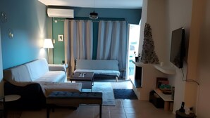 Ein Wohnzimmer mit einer Couch, einer Bank, einem Couchtisch, einem Fernseher und einem Kamin.