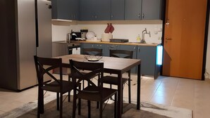 Eine kleine Küche mit Kühlschrank, Esstisch und Stühle sowie einem Spülbecken.