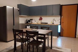 A compact kitchen with a refrigerator, a dining table with chairs, and a sink.