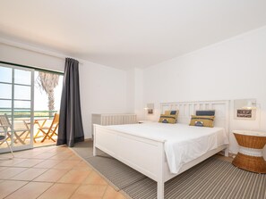 A bedroom with a bed, a window with a view, a chair, and a table. - CB GOLDEN 6.3A in Cabanas de Tavira (Cabanas de Tavira)