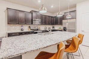 Enjoy the heart of your stay in this stylish kitchen with rich dark cabinetry and a spacious granite island. Modern appliances and warm-toned chairs create a chic atmosphere for cooking and gathering with loved ones. - 8BR house with private pool in Windsor Island (Davenport)