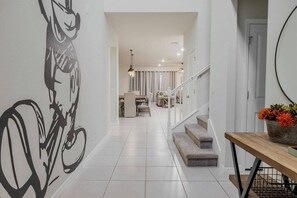 Welcome to a vibrant entryway with playful artwork and sleek tile flooring leading you to a bright, open layout. The warm wooden table and stylish decor create a cozy atmosphere, inviting you to relax and enjoy your vacation home. - 8BR house with private pool in Windsor Island (Davenport)