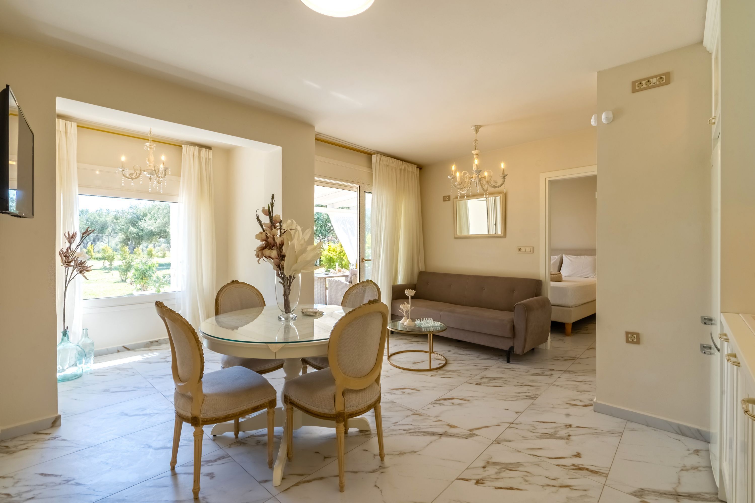 A dining area with a round table, chairs, and a vase of flowers.