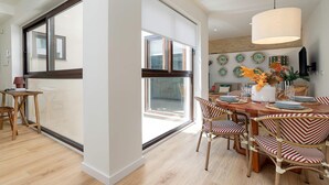 A dining area with a large window, wooden flooring, and a table set for four. - Genteel Home Feria Terrace 21 (Seville)