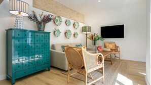 A living room with a teal cabinet, a rattan chair, a sofa, a flat-screen TV, and decorative plates on the wall. - Genteel Home Feria Terrace 21 (Seville)