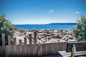 A wooden bench and a rocky beach with a clear blue sky. - Smugglers Cove - Short Walk to Beach (Amroth)